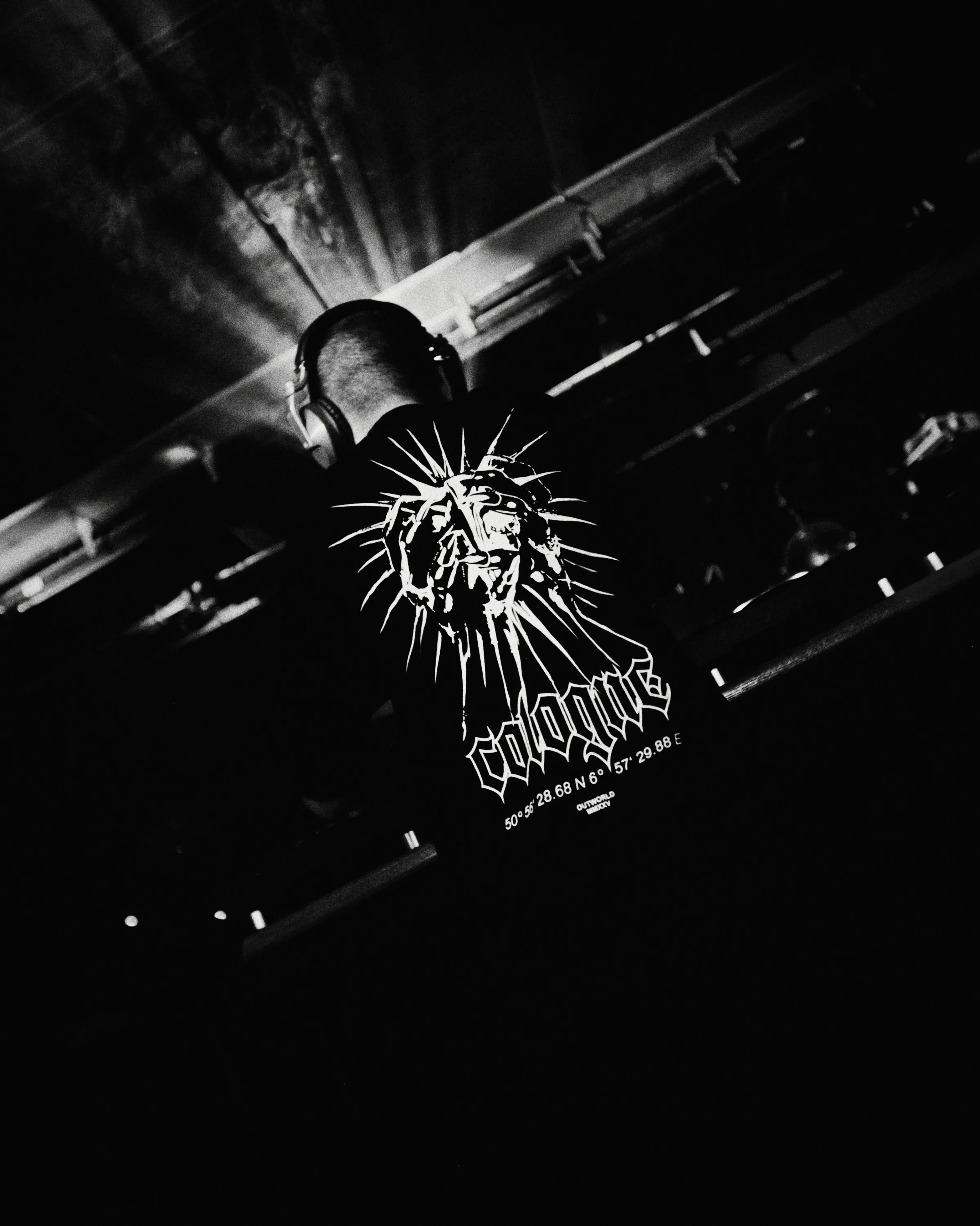 A DJ under stage lights in grainy, high-contrast black and white